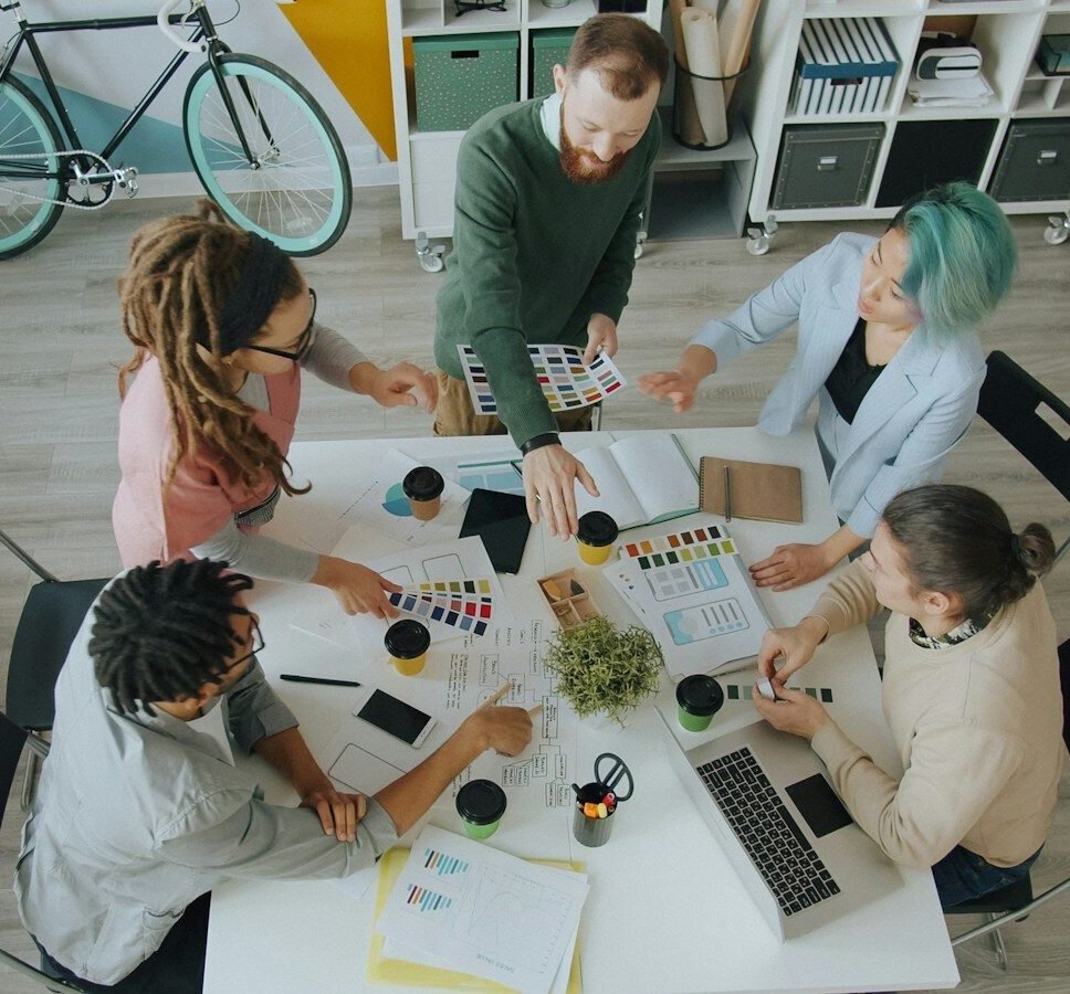 A group of four people collaborating around a table in a modern workspace